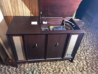 Front view of closed wooden console showing veneer finish and woven speaker grills