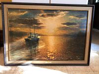 Full frontal view of framed golden sunset painting showing two sailboats reflective on water under cloudy sky.