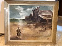 Full frontal view of the framed oil painting depicting a western scene with a cowboy on horseback and rustic buildings, signed Conrad 64.