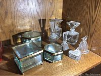 Photo of all nine items displayed on wood shelf showing glass boxes, perfume bottles, bell figurine, and heart container