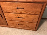 Close-up of the 3 drawers with recessed horizontal handles made of wood showing wood grain texture.