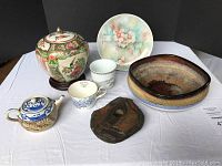 Full lot shown including vintage Asian pot, hand-painted plate, pottery bowl as flower pot, ceramic teapot, vintage Chinese mug, and stone frog figurine.