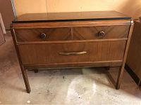 Front view of the vintage wooden bureau showcasing three drawers with wooden knobs and a brass handle, with visible scratches and wear.