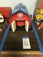 Front view of vintage Playskool Lock-Up Barn showing red barn structure with white doors and blue roof with white emblem and markings.