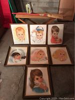 Seven framed vintage Northern Girl prints arranged on ground showing children's portraits with varied expressions.