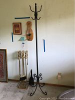 Fireplace tools set, metal coat rack, wall-mounted barometer and framed art on wall