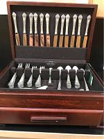 Open wooden case displaying 12 sterling dinner knives in upper lid row and bottom compartment with stacks of forks and spoons