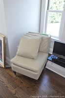 View of upholstered chair with matching pillows and wheels on front legs from side angle