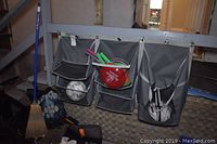 Two grey fabric wall organizers hanging on wall under stairs containing sports balls and rackets