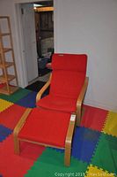 Red cushioned chair and matching ottoman on colorful foam play mats, angled views show chair and ottoman frame and cushions.