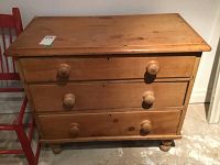 Front view of the pine dresser showing three drawers with round wooden knobs and surface wear.