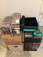 Image showing metal CD shelves loaded with assorted music CDs placed over cardboard boxes, including standard jewel cases.