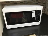Photo of the front of the white LG microwave model LMS1531SW showing black door window and control panel.
