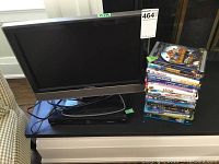 Front view of Insignia 19 inch TV, Phillips DVD player, and stacked children's DVDs on black table.