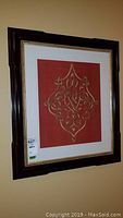 Image of first framed silk embroidery showing the full frame, which is dark wood with white and gold trim mat, and an ornate gold thread embroidery on deep red silk fabric.
