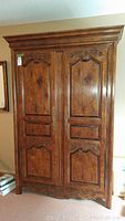 Front view of the wooden entertainment cabinet showing two large doors with carved details and brass handles.