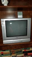 Front view of Toshiba 20-inch CRT TV showing screen, speaker grilles on sides, and front control panel with DVD player below.