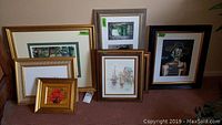 Overall group of 7 framed prints and paintings, arranged on carpet showing variety of sizes and styles.