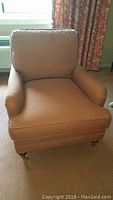 Front view of a custom houndstooth upholstered easy chair with globe leg casters, showing cushioned seat, back, and rolled arms.