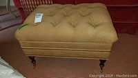 Front angled view of ottoman in setting highlighting overall shape, upholstery, and color.