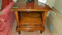 Front view of wooden end table showing drawer, shelf, and top surface