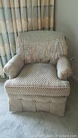 Front view of the custom rounded back club chair showing patterned upholstery and fringed throw over the back.