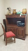 Full view of Bob Timberlake wood cabinet work station with three upper drawers, lower two cabinet doors, and chair with red seat placed beside it.