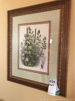 Framed botanical floral print hung on wall with gold ornate frame and matting, showing white and pink speckled flowers with green leaves and stems
