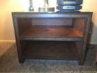 Front view of the leather wrapped lamp table showing the open middle shelf and nail head trim.