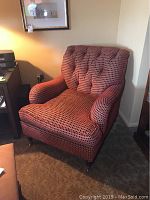 Full view of the custom club chair showing its shape, tufted back and red geometric upholstery.
