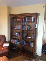 Front view of double walnut bookcase filled with books showing overall size and design.