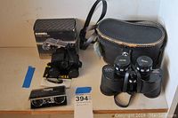 Three binoculars laid out: Manon 7x35 binoculars with case, Bushnell binoculars with box, and foldable compact binoculars.