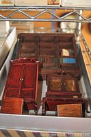 Miniature wood furniture pieces including armoire, bookcase, glass-front cabinet, and a small wooden chair.
