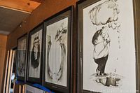 Photo showing four black and white framed prints hung on a wall, each approximately 17x21 inches, depicting golf-related humorous scenes by Gary Patterson. The frames are black with white matting.
