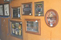 Wall-mounted vintage bar mirrors showcasing various beer brands for sale. Frames vary, some mirrors are oval and others rectangular.