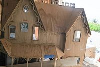 Front exterior view of the handcrafted unfinished wooden doll house showing stains and marks.