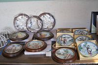 Group photo of 18 Asian inspired collector plates, 10 framed in round wooden frames, 8 unframed square plates with artwork depicting traditional Asian figures and scenes.
