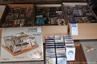 Overview photo showing multiple cassette tapes arranged alongside the teak wood cassette holder in original packaging.