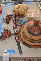 Top view of sword sheath with beadwork, leather tassels, tufted straw hat, woven hats, and decorative boxes