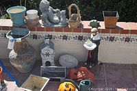 Photo showing 16 garden statues, vases, pots and decorative items arranged on tiled ledge and ground including a large vase, monkey cherub, monk statue, frog, pumpkin pot and others