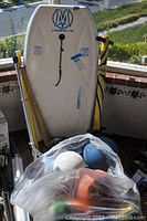 Morey boogie board, Razor scooter, and a plastic bag of balls all shown together on patio surface.