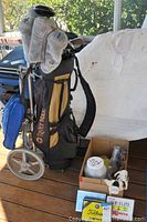 Full view of TaylorMade golf bag with clubs and the box of golf accessories including golf balls, tees, and gloves