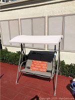 Front and side views of the covered patio swing showing the canopy, seat, and frame with cushion.