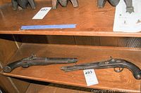 Wide shot of the two vintage Afghan pistols displayed on wooden shelves, showing overall condition and form.