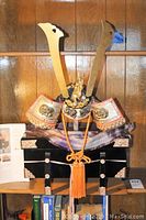Full view of the Japanese kabuto helmet on display stand with decorative box underneath.