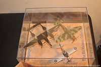 Photo showing three model planes inside clear display case from an angled top view.