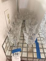 Front view of twelve stemmed goblets arranged in two rows on a tiled surface.