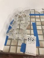 Eight Waterford Lismore crystal liqueur glasses arranged on a tiled surface showing the side view and overall lot display.