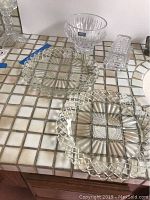 Four Waterford crystal items including Marquis bowl, butter dish, and two square platters on tile surface.