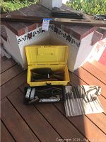 Wide shot of masonry tool assortment including yellow and black plastic tool trays, fabric tool roll and large metal level